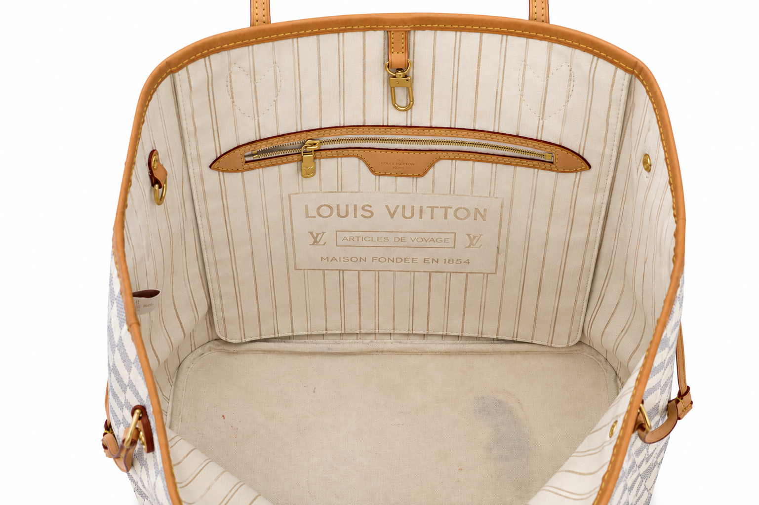 The interior of a Louis Vuitton handbag, showing the cream and beige pinstriped lining, a zippered pocket, and the Louis Vuitton brand label on the back wall.
