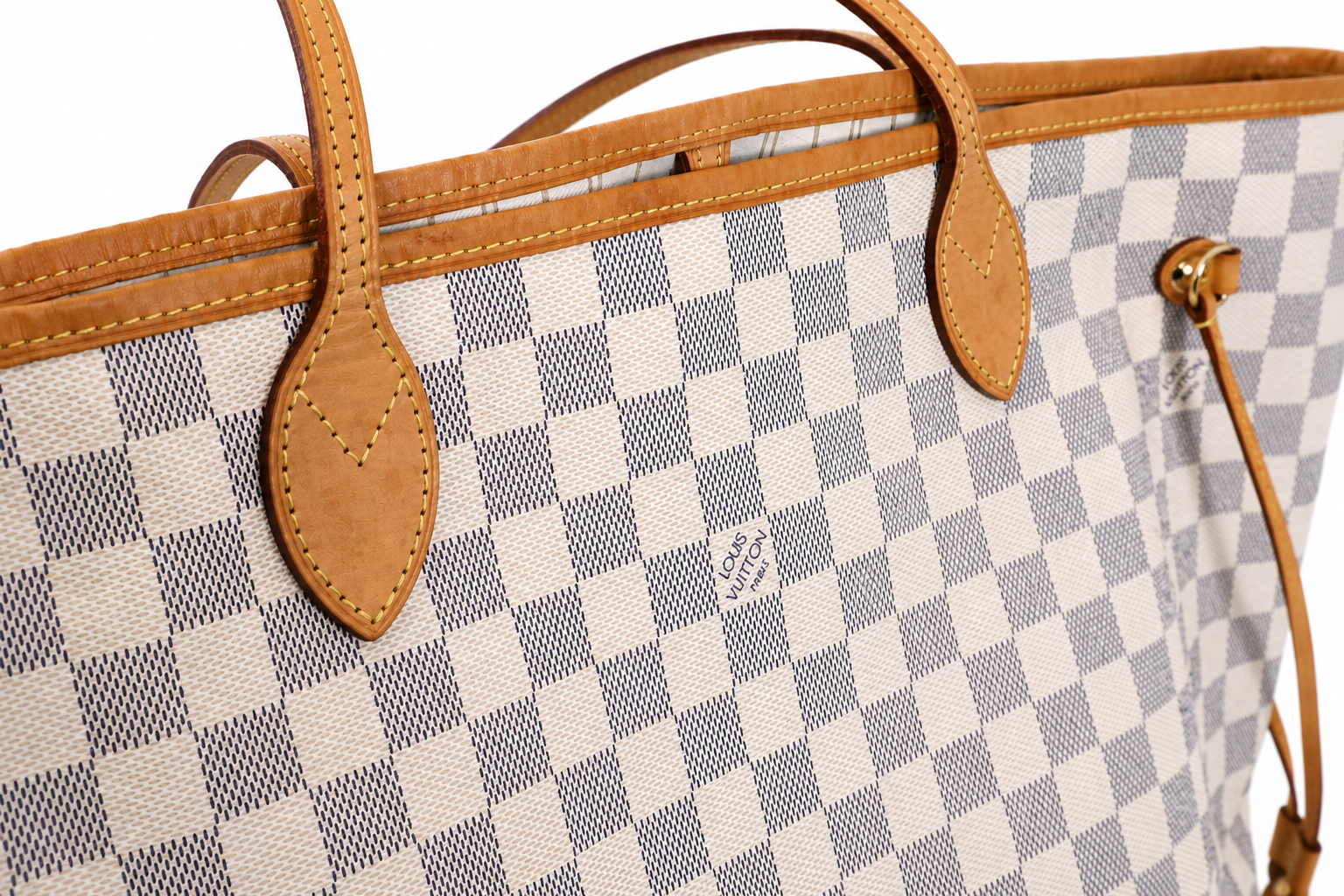 Close-up of a Louis Vuitton tote bag featuring the brand's signature Damier Azur canvas checkered pattern in beige and blue-gray, accented with tan leather trim and handles.