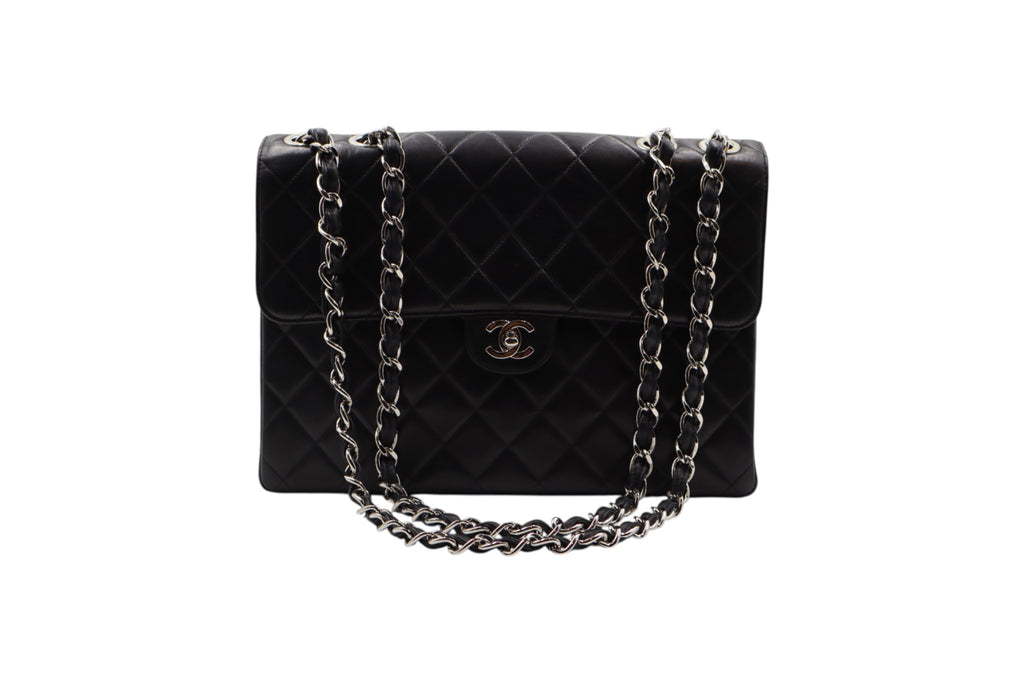 front view Chanel black quilted leather handbag with a silver-tone chain strap and a gold-tone interlocking CC logo on the front, set against a plain white background.