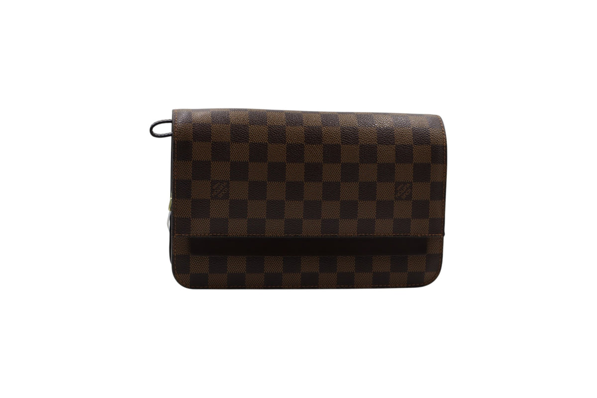 A Louis Vuitton clutch in the Damier Ebene checkered canvas, featuring a brown and dark brown checkerboard pattern with a black top loop, shown against a plain white background.