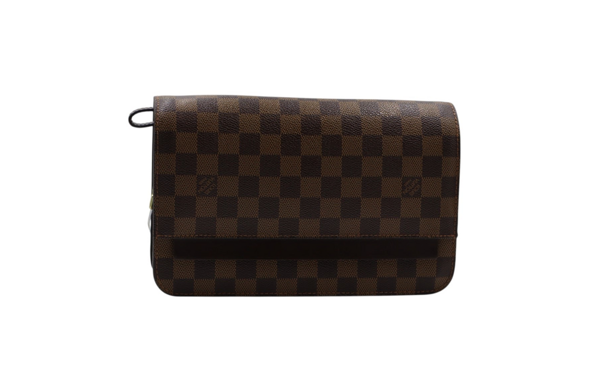 A Louis Vuitton clutch in the Damier Ebene checkered canvas, featuring a brown and dark brown checkerboard pattern with a black top loop.