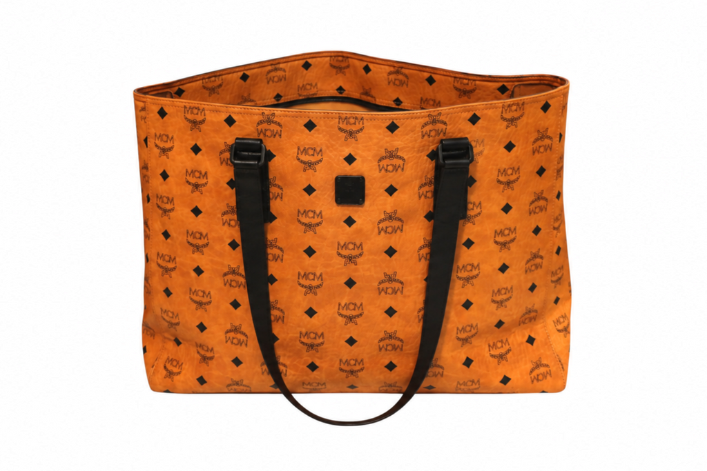 Front view of MCM cognac Visetos tote bag with black monogram print, black leather shoulder straps, and an open-top design on a white background.