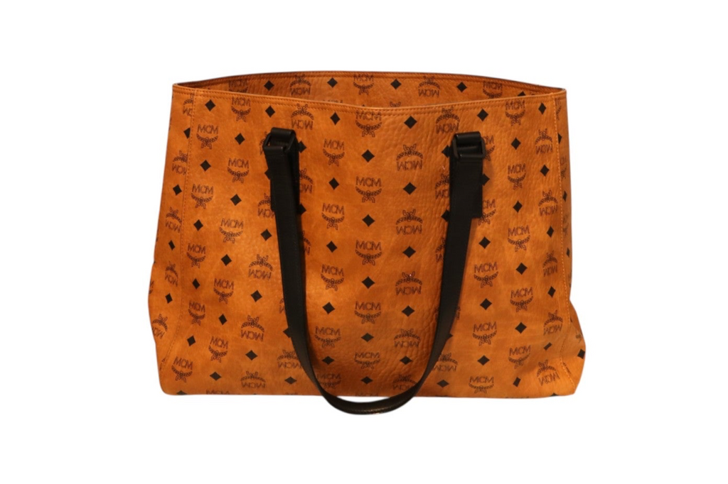 Back view of MCM orange Visetos tote bag with black monogram print, black leather shoulder straps, and an open-top design on a white background.