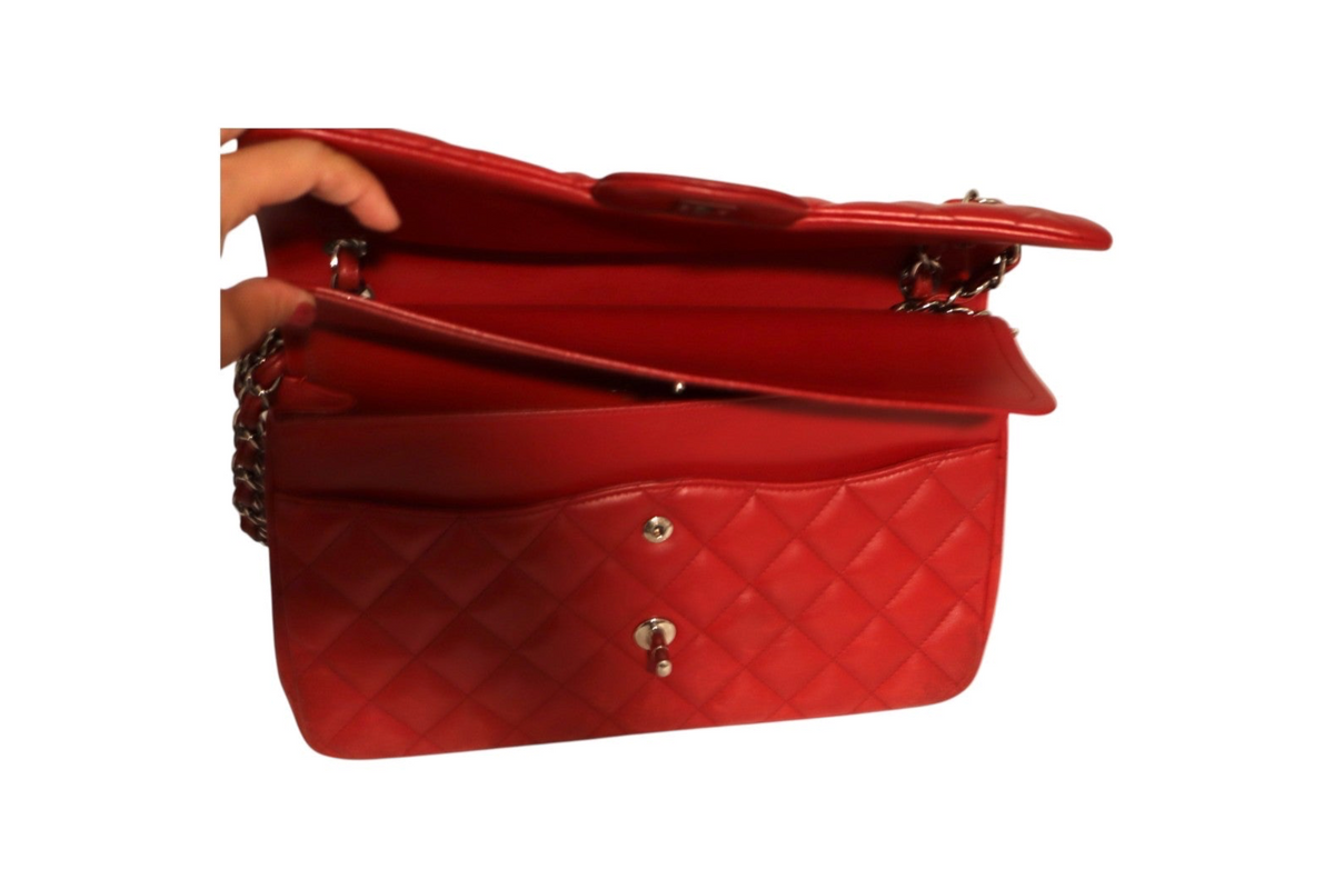 A red quilted Chanel leather shoulder bag with gold-tone chain strap details, shown open with a hand holding the top flap.