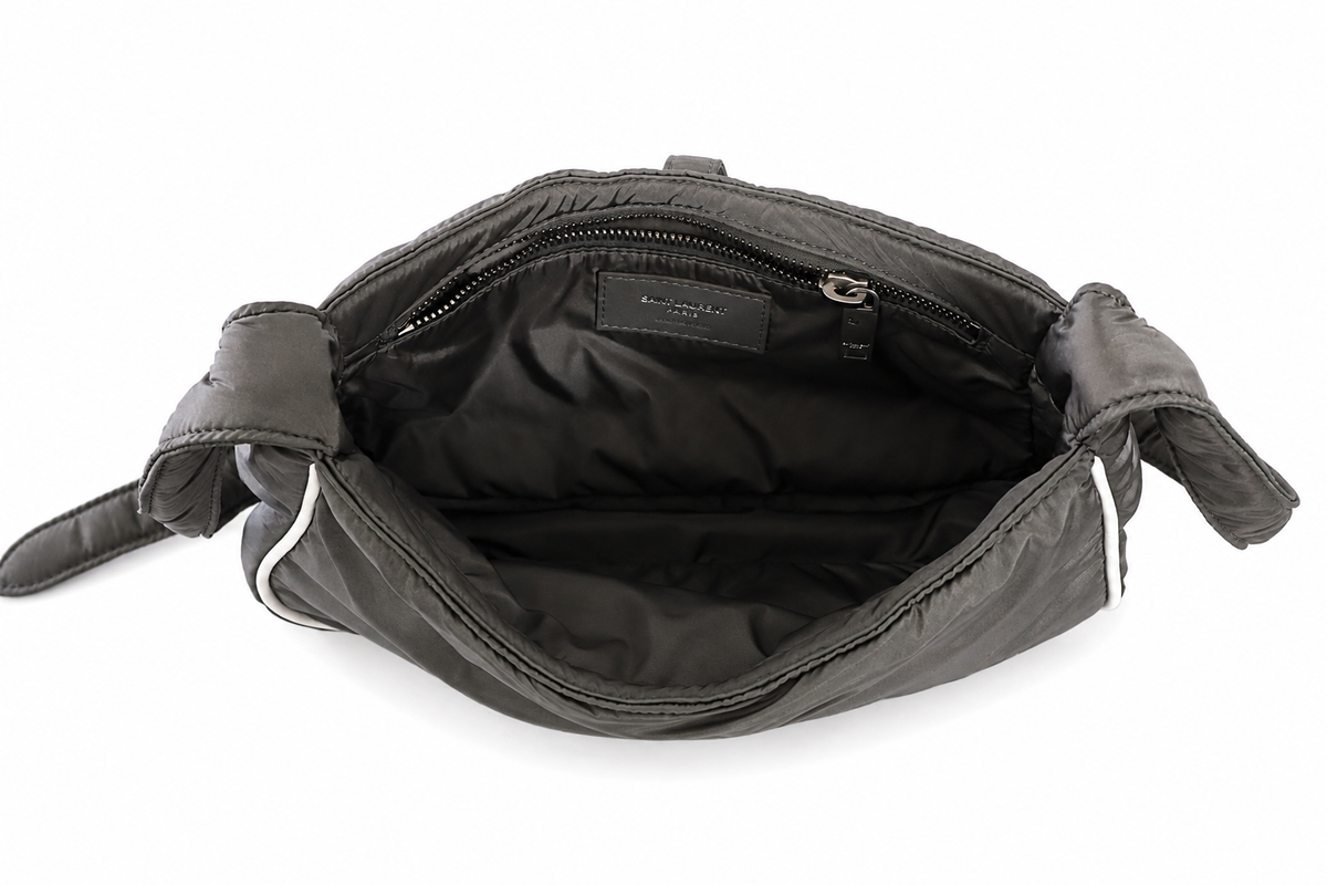 Yves Saint Laurent interior dark nylon shoulder bag with a padded interior, zipper compartments, and a small interior brand label, shown on a white background.