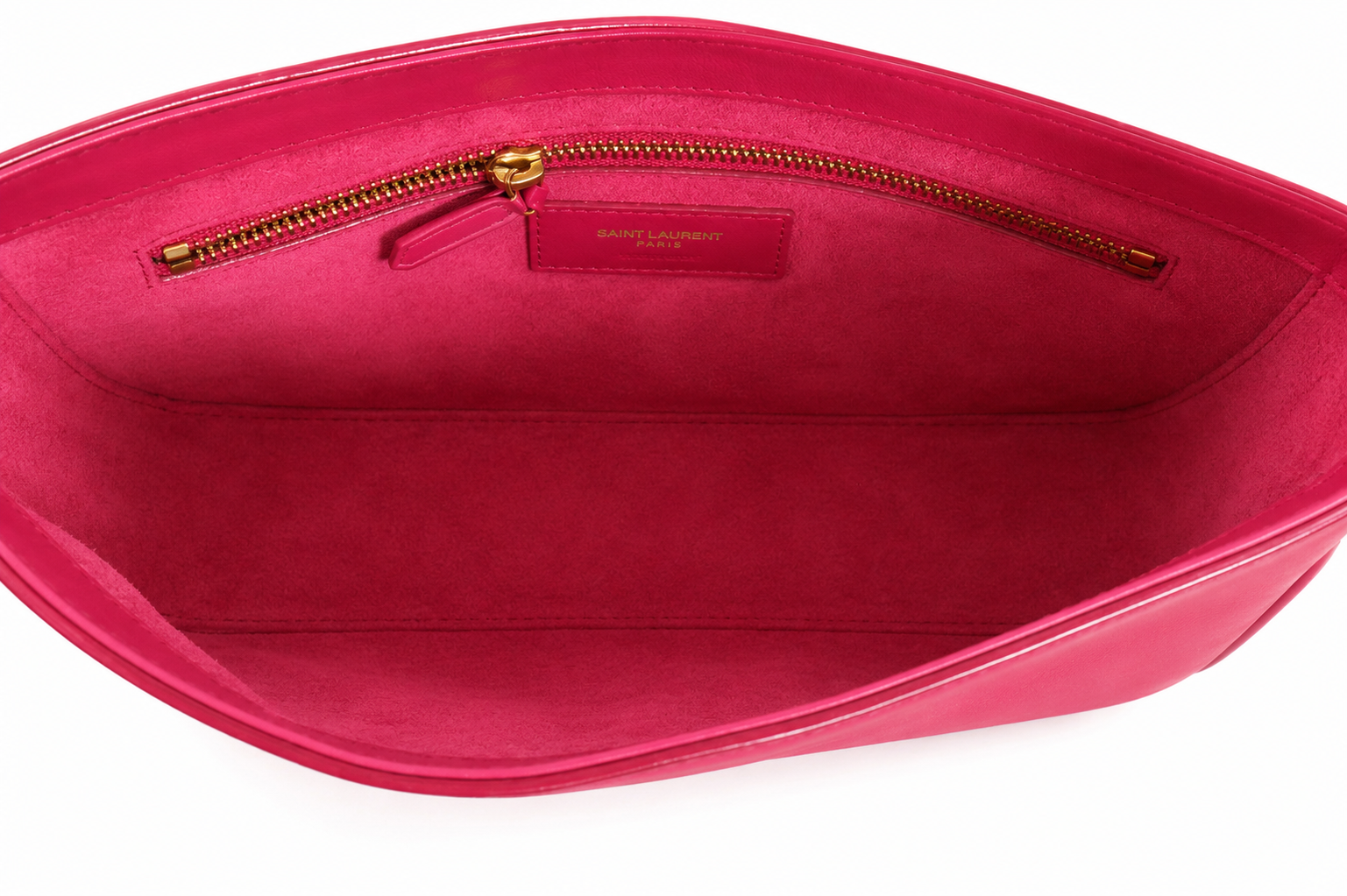 Yves Saint Laurent interior of a bright fuchsia pink leather bag, showing a suede-like lining, a gold-tone zipper track, and a small branded leather patch.