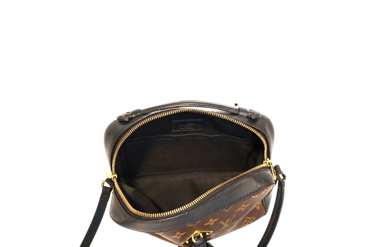 Top-down interior view of Louis Vuitton Monogram canvas crossbody camera bag with open gold-tone zipper, black fabric lining, interior slip pocket, and black leather trim on a white background.