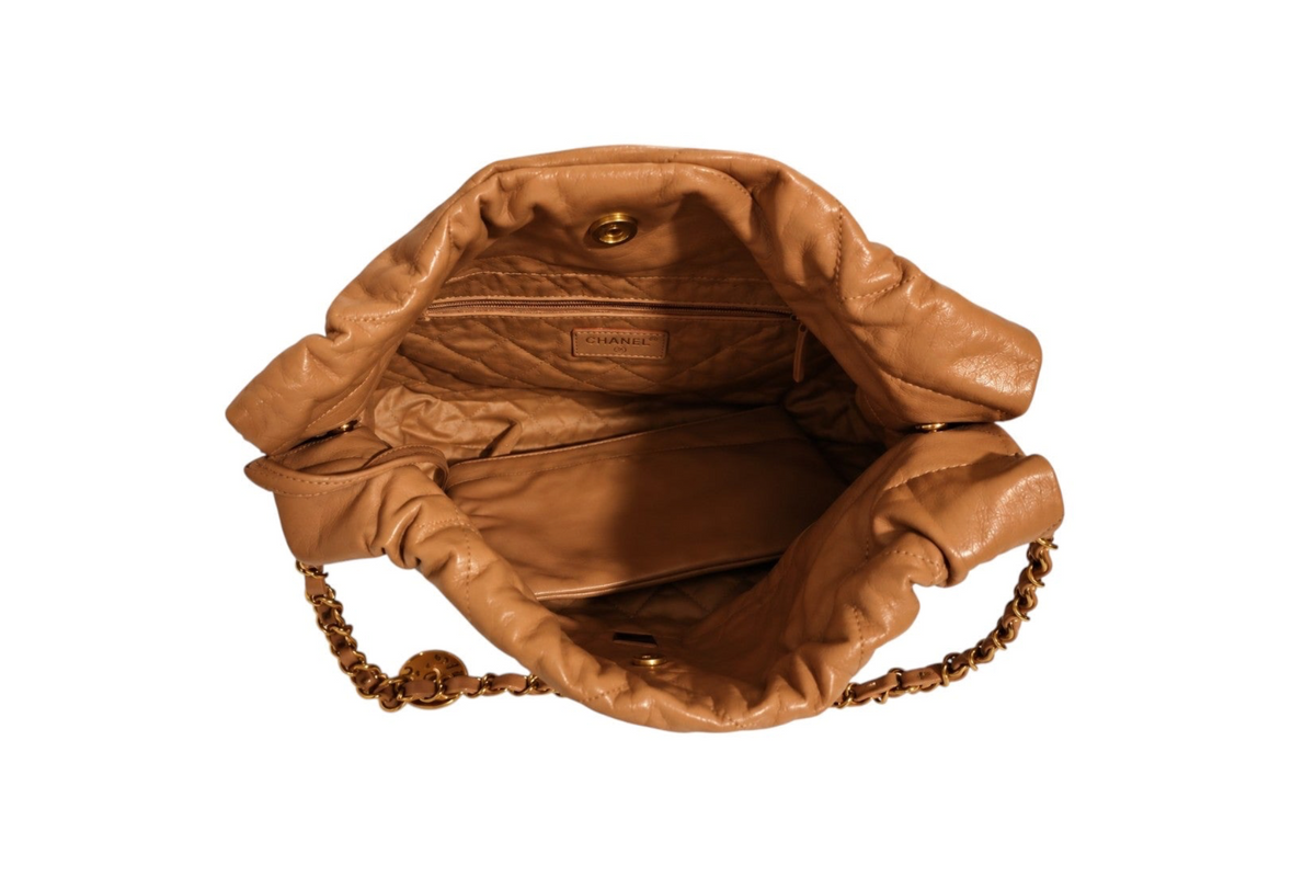 Top-down interior view of Chanel tan quilted leather shoulder bag with open ruched top, quilted lining, interior zip pocket, Chanel logo label, and gold-tone magnetic snap closure