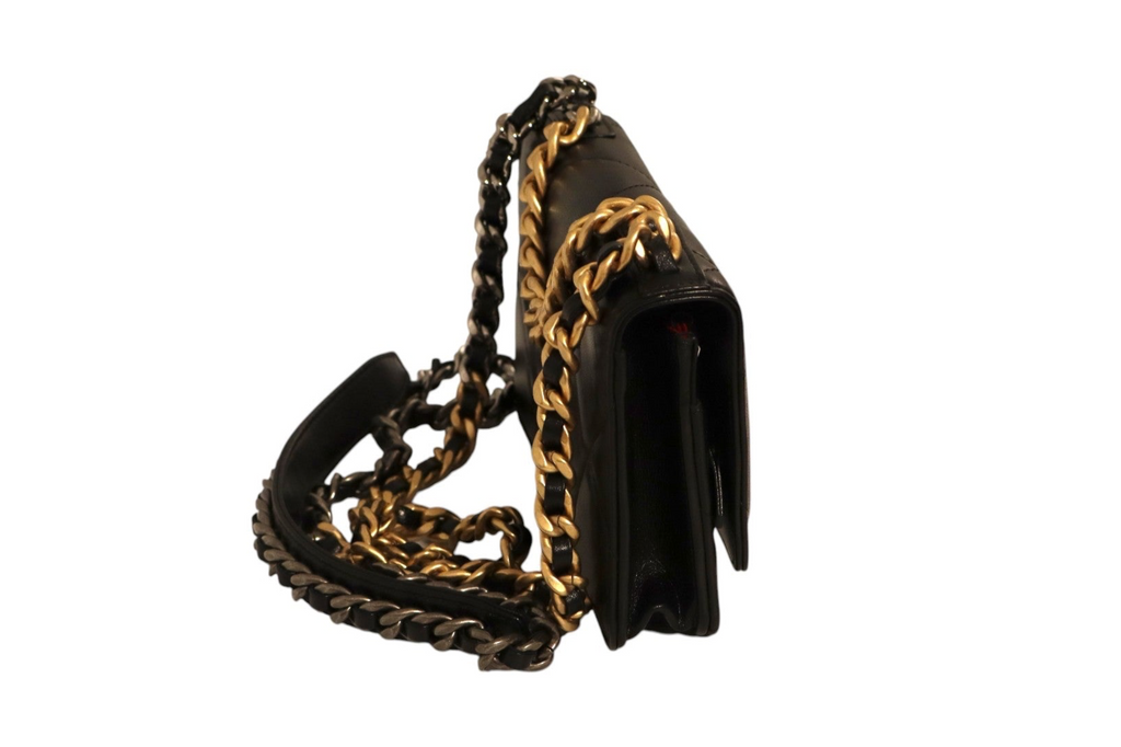 Side view of Chanel black quilted leather flap bag with gold-tone and dark metal chain detailing, interwoven leather chain shoulder strap, and structured gusseted sides