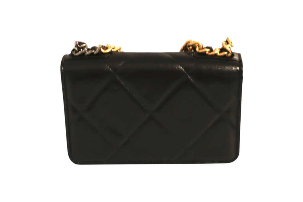Back view of Chanel black quilted leather flap bag with oversized diamond stitching and mixed gold-tone and dark metal chain straps