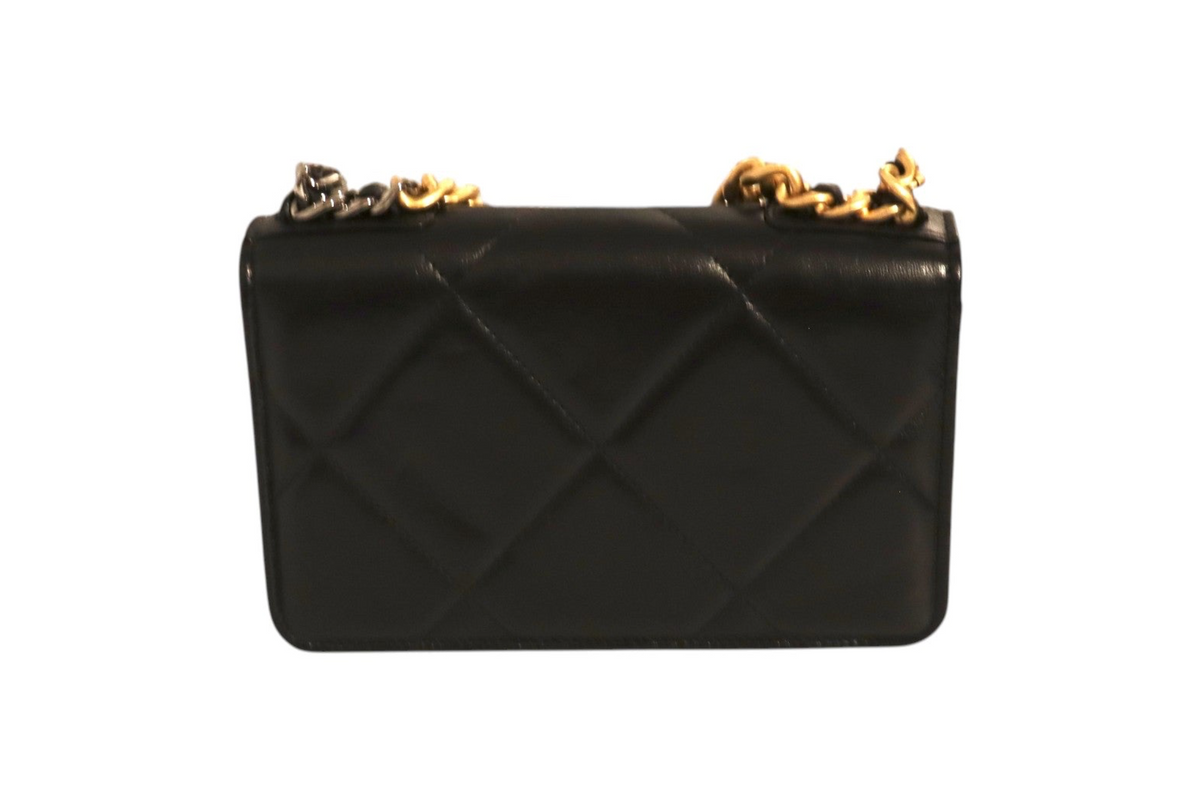 Back view of Chanel black quilted leather flap bag with oversized diamond stitching and mixed gold-tone and dark metal chain straps