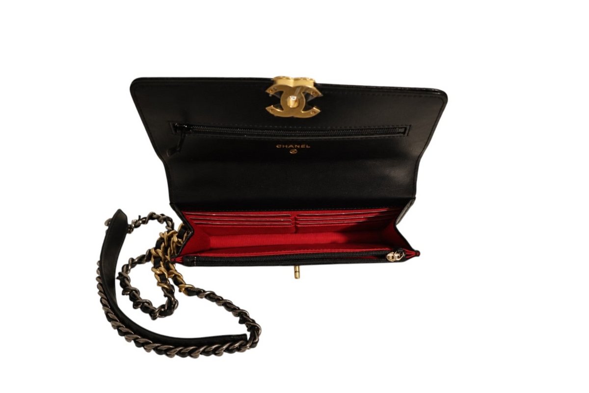 Top-down interior view of Chanel black leather flap bag with vibrant red lining, multiple card slots, zippered compartments, gold-tone CC clasp, and mixed-metal chain shoulder strap 