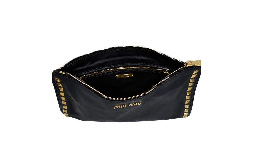 A black Miu Miu nylon pouch bag shown open, featuring gold-tone hardware, a gold zipper, and gold studs along the edges, with the 'miu miu' logo printed in gold on the front.