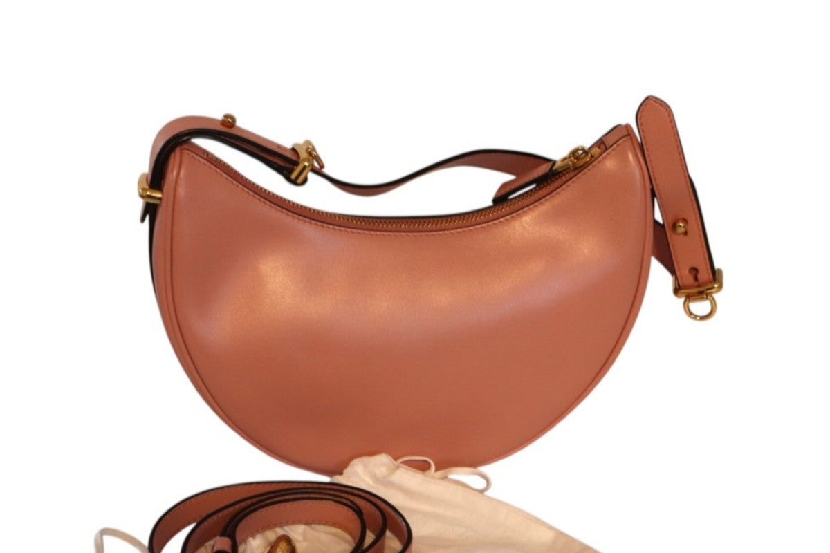 A Prada pink-colored leather crescent-shaped shoulder bag with gold-tone hardware, shown with its matching leather strap.