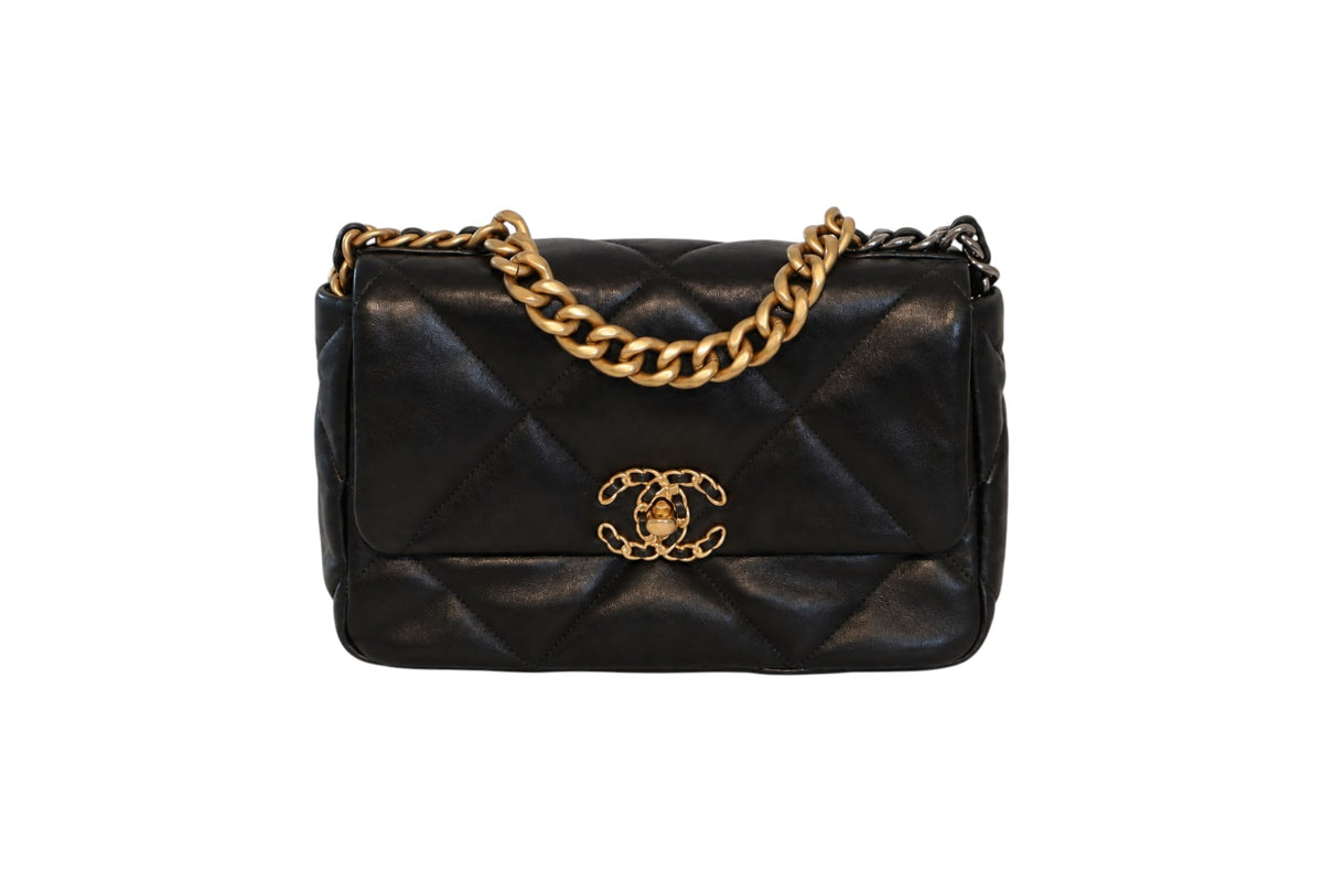 A black quilted leather Chanel flap bag with gold-tone hardware, featuring a gold chain strap and a prominent interlocking CC logo on the front flap.
