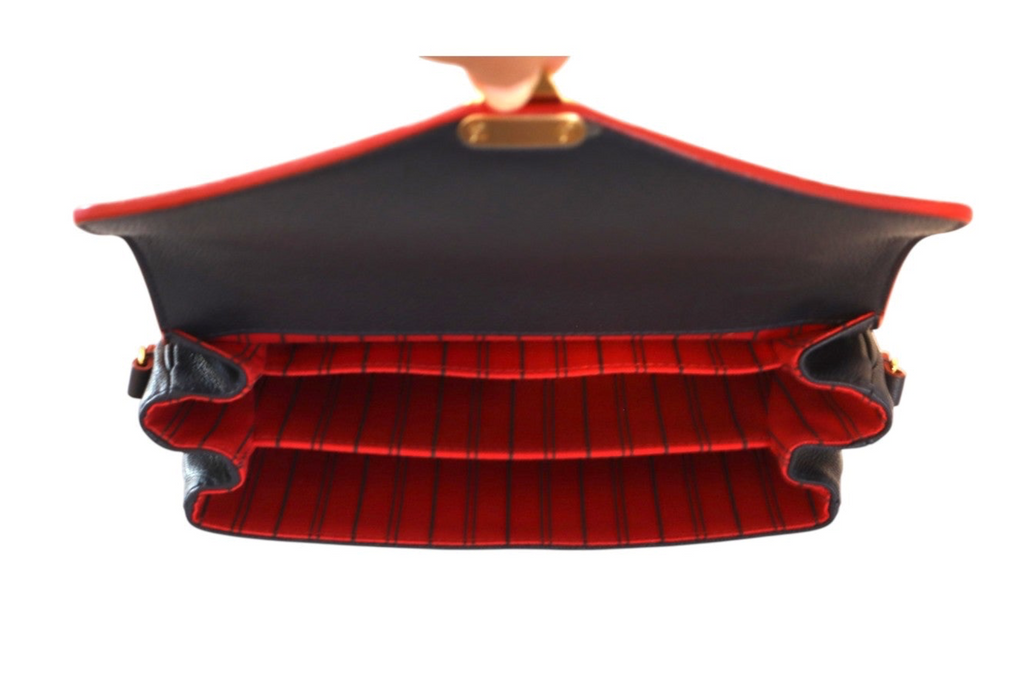 A structured Louis Vuitton navy leather shoulder bag shown open from a top-down view, featuring a black exterior with red piping and a red-and-black vertically striped interior.