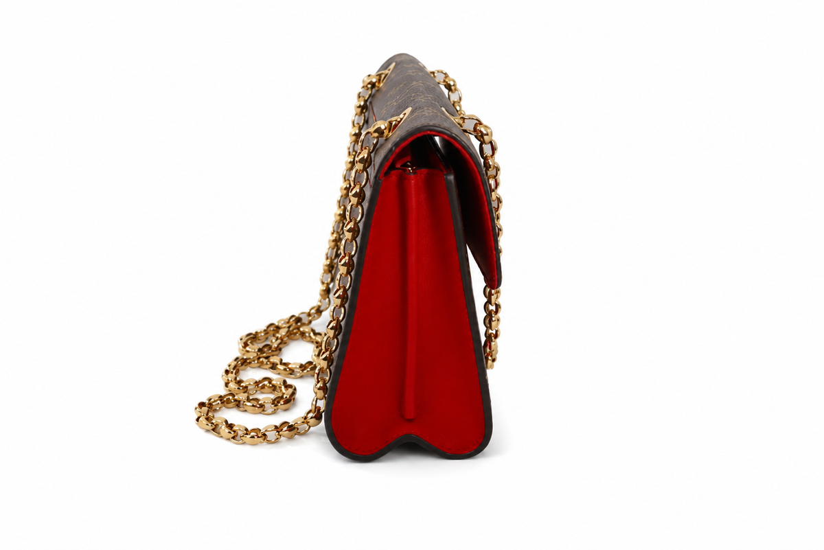 Louis Vuitton shoulder bag with a dark brown textured exterior, a vibrant red interior lining, and a gold-tone chain strap, shown from a side profile view on a white background.